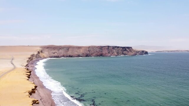 Drone aerial view, red sand beach, big waves and road in desert cliff blue sea clear sky blue. Paracas National Park, Peru 4k.
