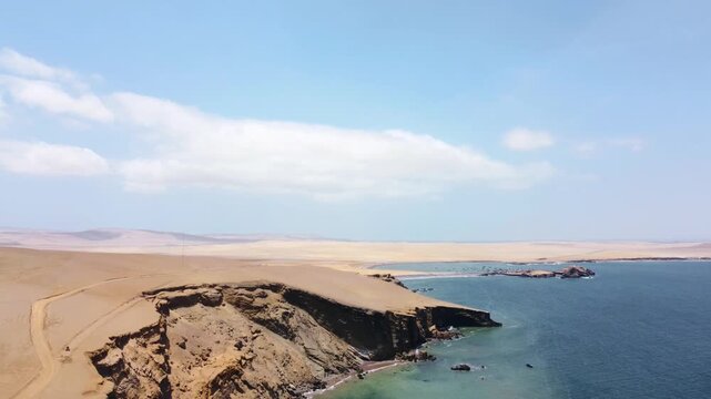 Drone aerial view, red sand beach, big waves and road in desert cliff blue sea clear sky blue. Paracas National Park, Peru 4k.