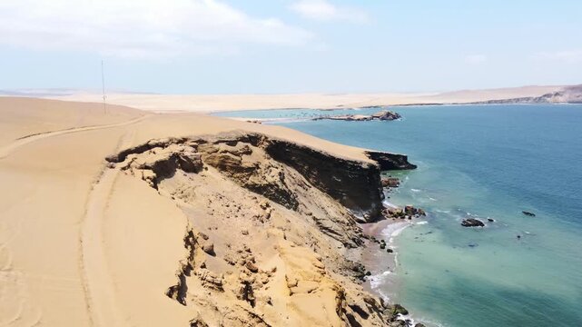 Drone aerial view, red sand beach, big waves and road in desert cliff blue sea clear sky blue. Paracas National Park, Peru 4k