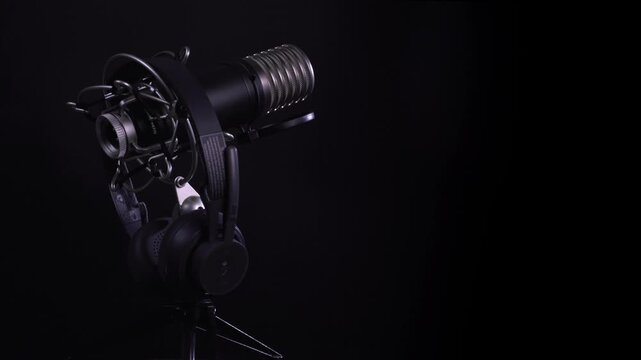 Professional Condenser Microphone and Headphones Rotating on Dark Background