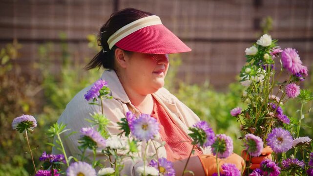 A Dedicated Gardener Tends to Colorful Flowers, Embracing Nature's Beauty While Wearing a Sunshade and Bringing Life to Her Lush Floral Garden