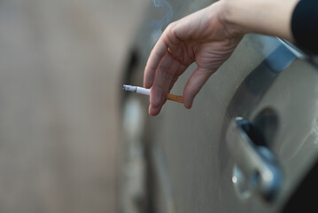 Female Hand Holding Cigarette Outside Car With Soft Smoke Detail