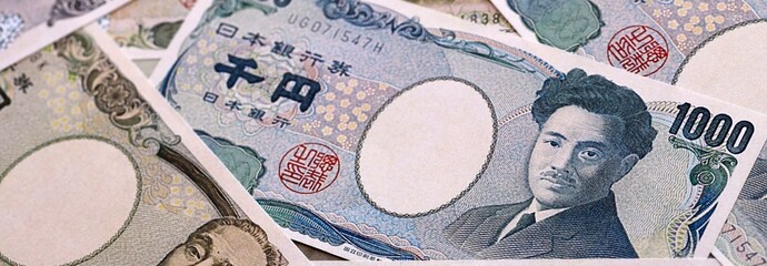 Japanese yen money bills pile on table. Japan banknotes of JPY currency close up. © Larysa