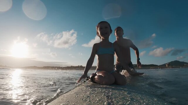 Kid surfs. Little girl learns surfing with her father and tries to keep balance on the surf board