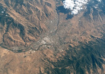 Aerial view of a city nestled in a valley, surrounded by arid mountains, capturing urban sprawl