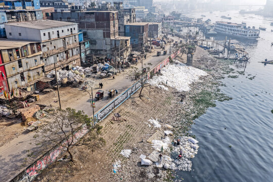 Aerial view of the Buriganga River's bank, where buildings loom over a landscape marred by pollution and piles of waste, Dhaka, Dhaka Division, Bangladesh.