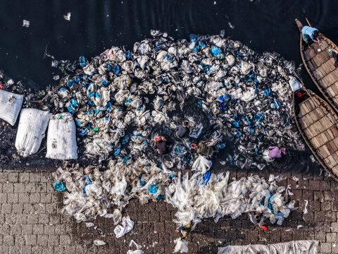 Aerial view of an environmental nightmare as discarded plastics and waste choke the Buriganga River's edge, contrasting sharply with the traditional boats, Dhaka, Dhaka Division, Bangladesh.