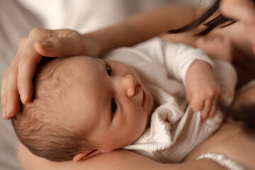 Newborn baby lying on bed and sleeping at home. Close up views of infant hands, feet and parent touching baby during daily childcare routine.