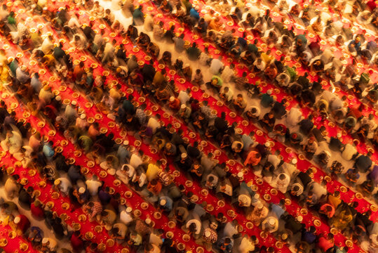 Dhaka, Bangladesh - 25 February 2026: Aerial view of vibrant red carpets and countless individuals gathered for Iftar at the mosque, a sea of colorful clothing beneath.