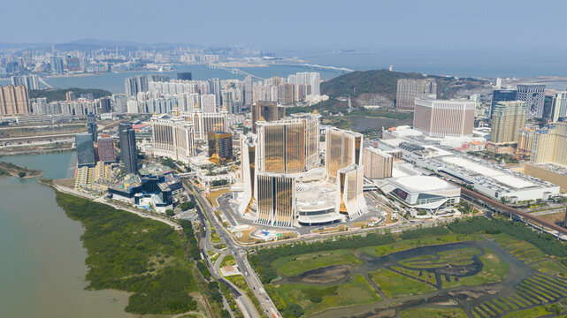 Cotai, Macao - 18 February 2026: Aerial view of the dazzling, golden Grand Lisboa Palace standing tall amidst a vibrant cityscape, framed by the calm, reflective waters and lush greenery.