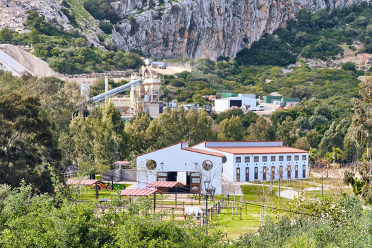 Manilva, Spain - 18 February 2026: View of the white horse stable farm building standing out against the green trees, with the quarry blending into the mountains behind it.