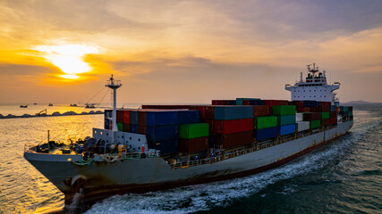 Cargo ships and container ships sail the seas during sunset.