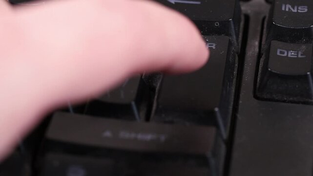 Finger hitting the Enter key on a dirty used keyboard, technology and workspace concept.