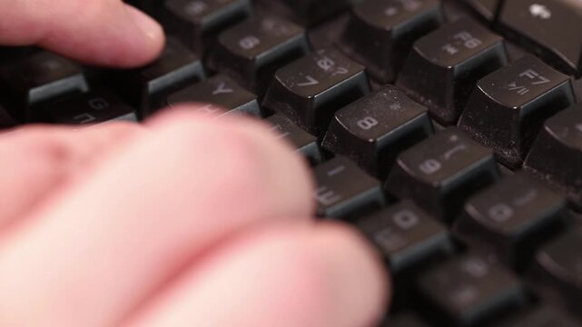 Close-up of fingers typing on a neglected uncleaned black keyboard, hygiene and workspace concept.