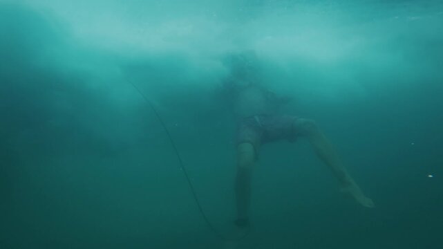 Surfer dives under the wave. Underwater footage of the surfer diving under the wave with surfing board