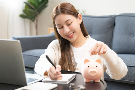 Financial, asian young woman, girl putting stack coins on table for calculate cost sitting in living room at home, financial plans to spend enough money on his income for saving money and payment.