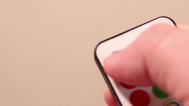 Macro close-up of a finger pressing the red ON button on a remote control.