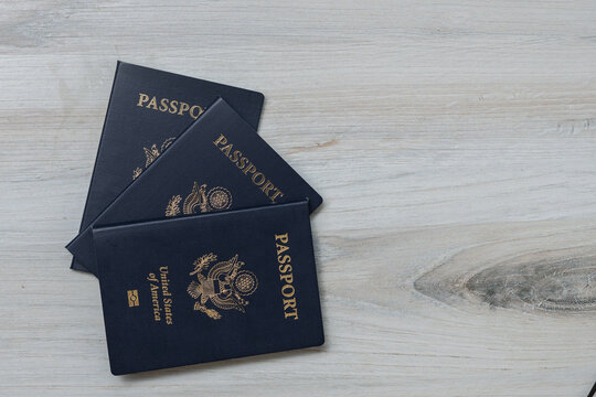 Photo of Three American passports fanned out on a white wooden surface, flat lay, copy space.