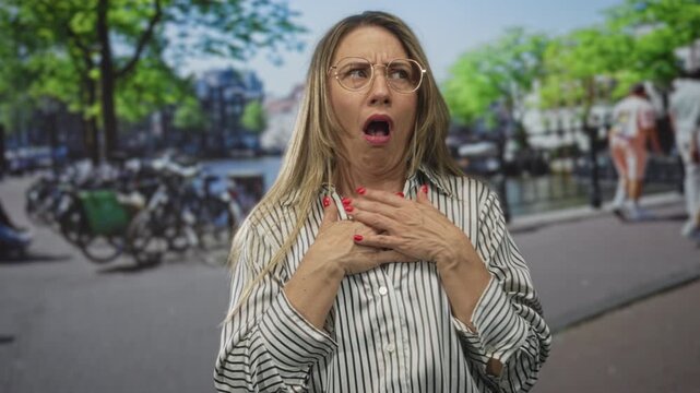 Woman recoils with raised hand and furrowed brow near bicycle by canal on street; disgust shock revulsion.