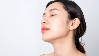 하얀 배경 앞에서 눈을 감고 평온한 표정으로 깊은 숨을 들이마시며 휴식을 취하고 있는 깨끗하고 건강한 피부를 가진 젊은 아시아 여성의 아름다운 옆모습 클로즈업 사진입니다.