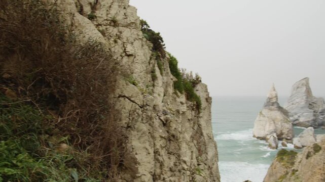 Beautiful seascape on the background of rocks. Famous Portuguese Ursa Beach. Beautiful panorama of the Rocky shore with incoming turquoise waves.