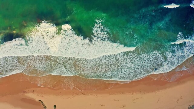 Beautiful beach with yellow sand during rolling waves to the shore. Top view of the sandy ocean shore on  sunny day.  Aerial view of the beautiful coastline of the azure Atlantic Ocean. Relaxing scene