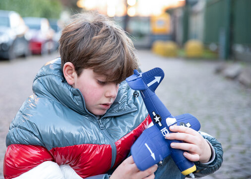 Close-up Portrait of Teenage Boy Examining Remote Controlled Airplane Outdoors