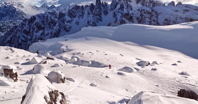 Aerial footage of a ski mountaineer in a snowy alpine ridge in Dolomites. Winter landscape, backcountry adventure, and solitude in breathtaking mountain scenery captured in 4K.