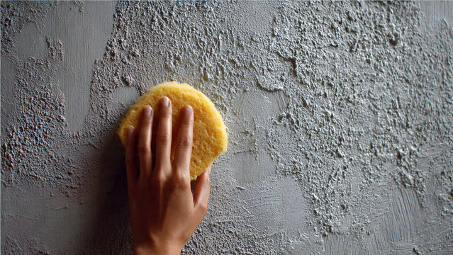 Mortar plaster application on wall with focused tool grip hand in high contrast construction scene. (98 chars)