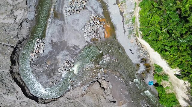 Aerial view of volcanic rocky ground with muddy water flow creating natural texture pattern aerial