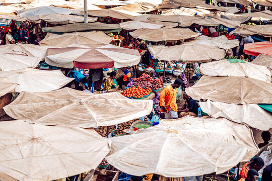 Kampala, Uganda - 28 March 2024: View of a bustling market under a sea of umbrellas, where vibrant produce and colorful clothing create a lively tapestry of commerce.