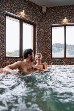 Romantic couple enjoying spa day, relaxing in the warm bubbling jacuzzi hot tub