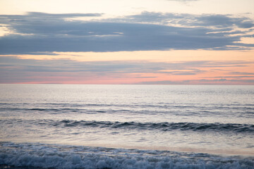 Fototapeta premium Dreamy beach sunset with soft waves and warm evening glow