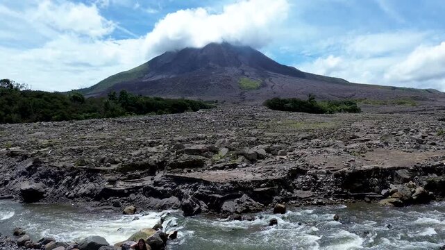Dramatic volcanic mountain landscape with rocky terrain and flowing river under cloudy sky