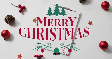 Showing spiral-bound notepad MERRY CHRISTMAS text on white table with red ornaments, pine cones © vectorfusionart
