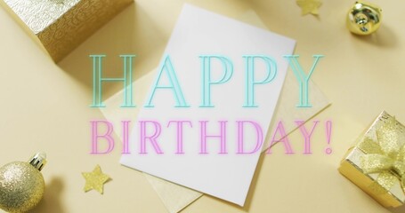 Displaying white card sitting on beige envelope on pale tabletop, with gold gifts, birthday text