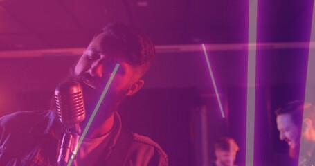 Naklejka premium Singing singer in casual jacket leaning toward vintage mic stand on stage with LED tubes, amps