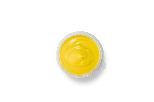 Smooth creamy yellow cheese sauce in small plastic cup isolated on white background top view fast food dipping sauce concept
