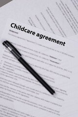 Childcare agreement contract on desk, legal document about child care services, parental responsibilities, and family support concept.