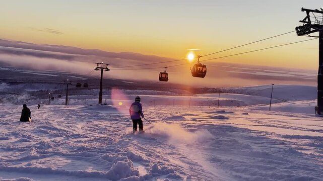 The atmosphere is cinematic and peaceful: glowing sunset light, drifting mountain fog, and a ski lift moving slowly in the background.