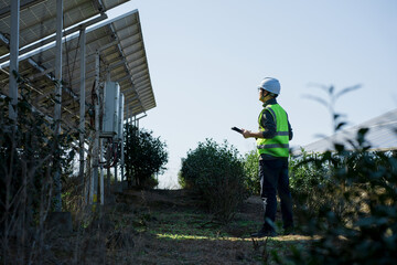 Solar power plant technician inspecting photovoltaic panels with handheld device outdoors © zhu difeng