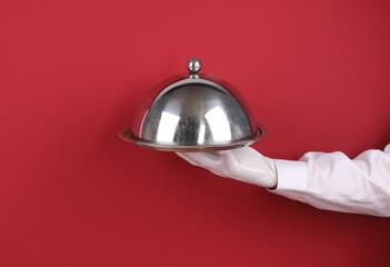 Waiter's hand with a tray isolated on a red background
