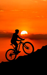 Fototapeta premium Silhouette of a cyclist riding uphill at sunset, creating a dynamic and adventurous scene