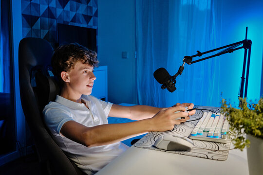 Young boy streaming video games at neon gaming setup