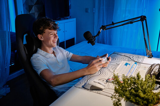 Happy young gamer teen playing video game streaming online
