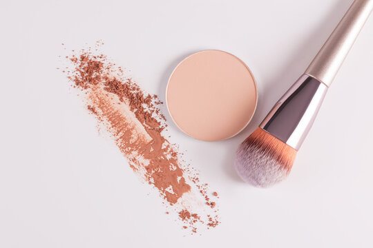 Compact face powder with makeup brush on white background