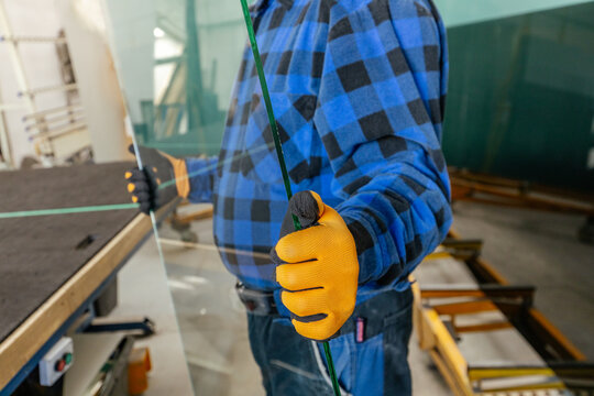 Glass Studio. A glassmaker holds a pane of glass in his hands. A local craft workshop, professional handwork. Financial and business concept. Close up