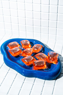 Laundry capsules on a blue dish against tiled background