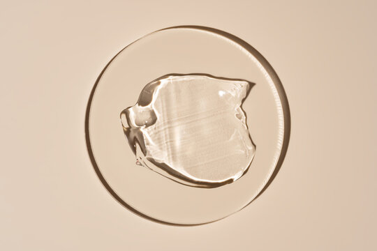 Cosmetic gel sample in a clear dish on beige background