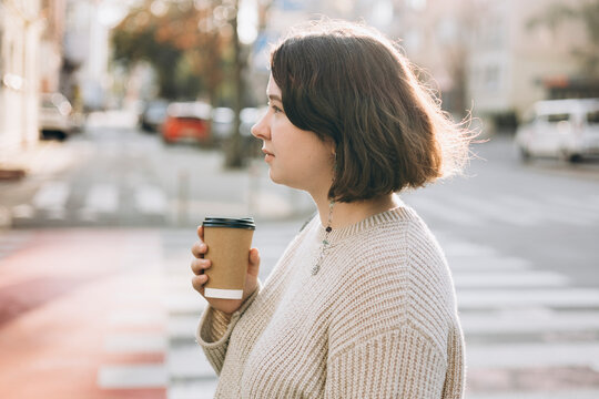 Woman with coffee cup on sunny city street